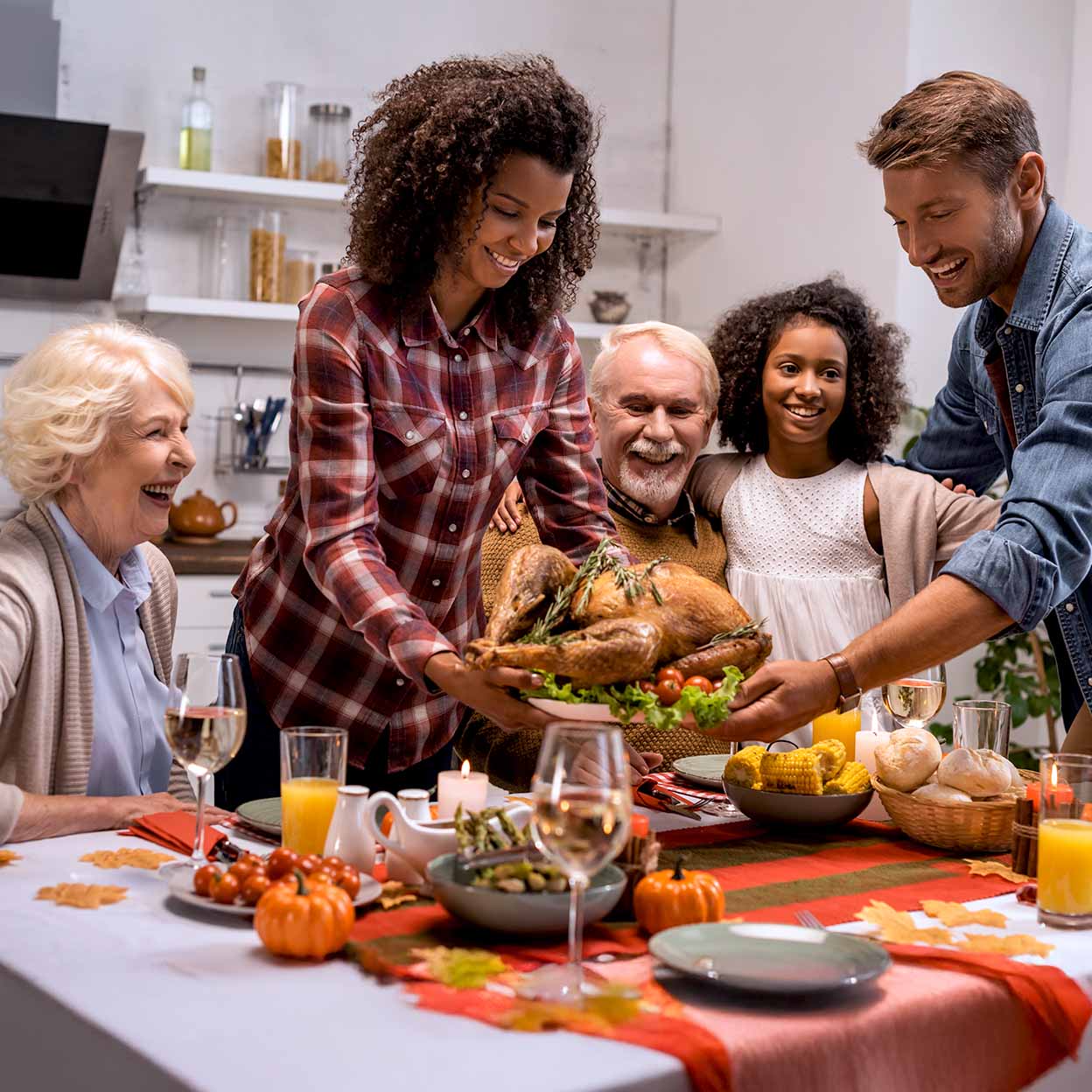 Family sets a roasted turkey on a festive Thanksgiving table, smiling together